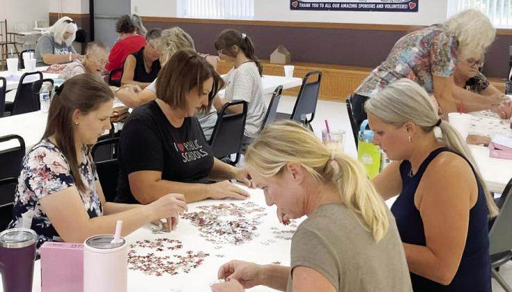 ABOVE: The Piece Makers, this year's first place team, work intently on their challenge in the Brady Days Puzzle Race on Aug. 2. LEFT: The puzzle race attracted a wide range of contestants this year, with both young and old joining the fun. (Photos courtesy Marge Spencer)