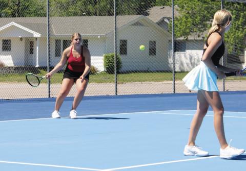 Peyton Hilbers plays a serve during a doubles match at York last week, while her teammate Briony Aden stays ready at the front of the court. (Leader photo by Megan Aden)