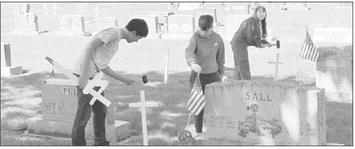 Pictured from left: Gothenburg FFA members Benjamin Mendez, Jonathan Scott, and Abigail Scott, place crosses and flags at the Gothenburg Cemetery for Memorial Day. (Photo courtesy Gothenburg FFA)