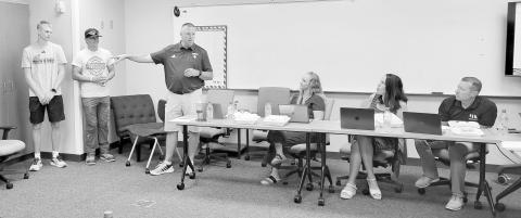 Gothenburg AD Marc Mroczek, standing, recognized Bryson Neels, left, and Jax Rickertsen as state track medalists during the July 13 school board meeting. Also pictured, from left, are school administrators Maggie Tiller, Tomye McKenna, and Seth Ryker. (Leader photo by Ellen Mortensen)
