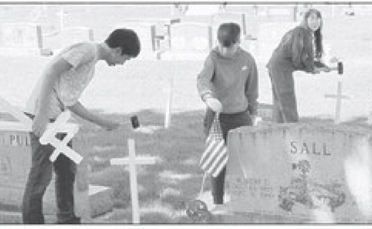 Pictured from left: Gothenburg FFA members Benjamin Mendez, Jonathan Scott, and Abigail Scott, place crosses and flags at the Gothenburg Cemetery for Memorial Day. (Photo courtesy Gothenburg FFA)